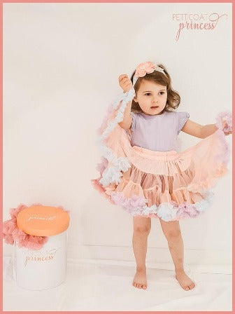 Girl dancing in dusty pink tutu with soft pastel rainbow ruffles