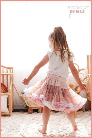 Girl dancing in dusty pink tutu with soft pastel rainbow ruffles